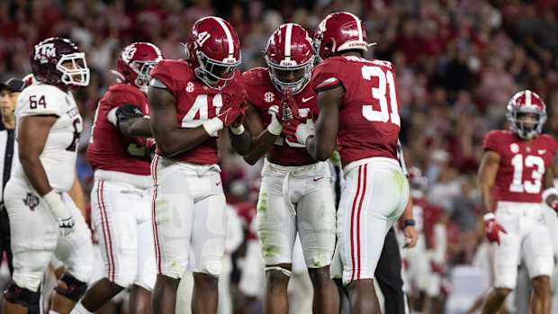 Chris Braswell, Dallas Turner and Will Anderson Jr. celebrate